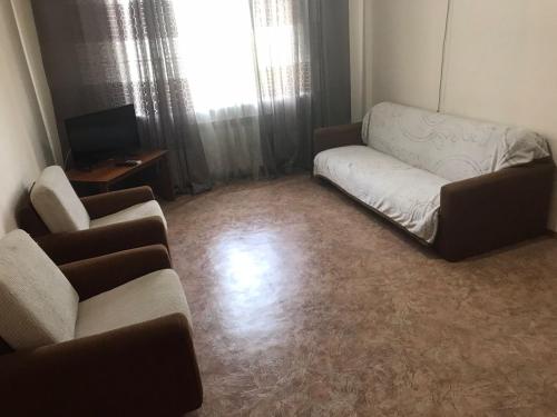 uma sala de estar com um sofá e duas cadeiras em Двухкомнатная Арбат em Shymkent