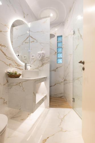 a white bathroom with a sink and a shower at RODAVGI APARTMENTS in Andros