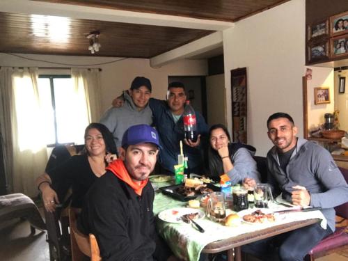 eine Gruppe von Menschen, die um einen Tisch sitzen in der Unterkunft Family Hostel in Perito Moreno