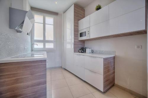 une cuisine avec des armoires blanches, un évier et une fenêtre dans l'établissement IMMOGROOM - Palais des festivals within walking distance - balcony - wifi -, à Cannes