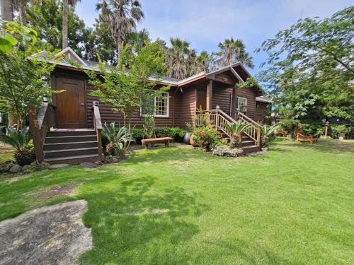 a wooden house with a lawn in front of it at Valley Village in Seogwipo