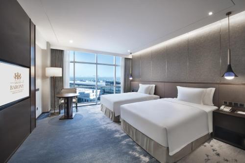 una camera d'albergo con due letti e una televisione di Grand Barony Qingdao Airport Hotel a Qingdao