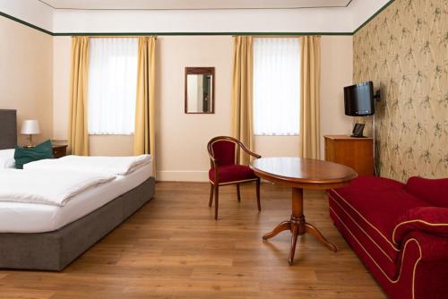 ein Hotelzimmer mit einem Bett, einem Tisch und einem Sofa in der Unterkunft Boutique-Hotel Amalienhof in Weimar