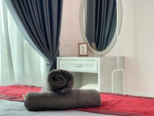 a pile of towels on a bed with a mirror at Century Suria Aparment Langkawi by Zervin in Kuah