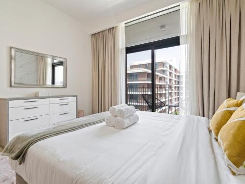 a bedroom with a white bed with towels on it at Fantastic 1 BR in Park Point - Dubai Hills in Dubai