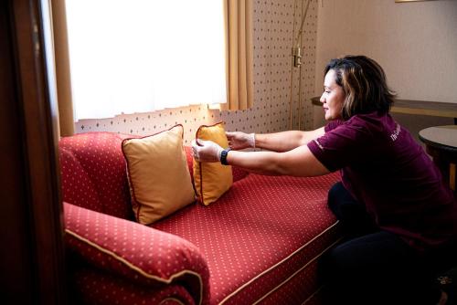 a woman sitting on a couch putting pillows on a couch at Boutique-Hotel Amalienhof in Weimar