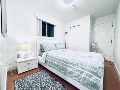 a white bedroom with a bed and a window at Charming 1BR near Metrotown DT Burnaby/ Vancouver in Vancouver