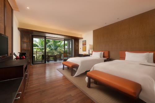 een hotelkamer met 2 bedden en een televisie bij Le Méridien Shimei Bay Beach Resort & Spa in Wanning