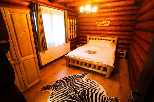 1 dormitorio con 1 cama en una cabaña de madera en Cazare Casa Suw Toplita en Măgheruş