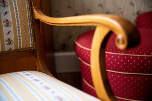 a close up of a red chair with a wooden handle at Boutique-Hotel Amalienhof in Weimar
