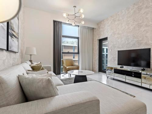 a living room with a couch and a tv at Fantastic 1 BR in Park Point - Dubai Hills in Dubai