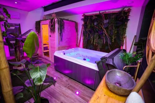 - une baignoire dans une pièce ornée de plantes et de lumières violettes dans l'établissement L'Évasion Loveroom, à Sarreguemines