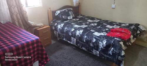a bedroom with a bed with a black and red blanket at Orboma Masai homestay in Sekenani