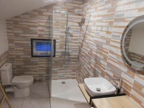 Gîte garde-barrière 2 chambres في Saint-Guen: حمام به مرحاض وتلفزيون على الحائط