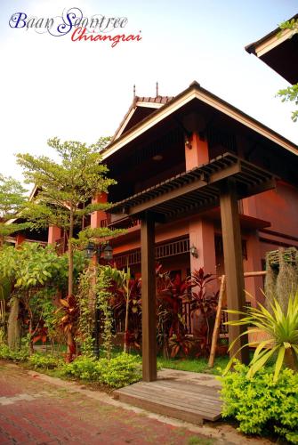 a building with a wooden porch in front of it at Baan Soontree Resort in Chiang Rai