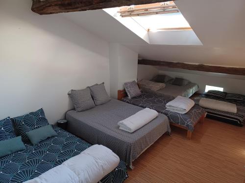 een zolderkamer met 3 bedden en een bank bij Nid Charentais Angouleme pool jacuzzi in La Poterie