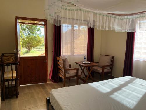 1 dormitorio con cama, mesa y ventana en Lake Jipe Eco Lodge en Tsavo West National Park