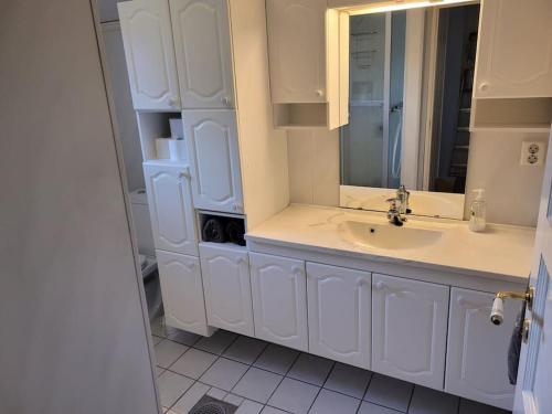 a white bathroom with a sink and a mirror at Trivelig hus sentralt på Storslett in Storslett