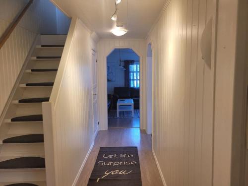 a hallway with a staircase with a sign that says let life surprise you at Trivelig hus sentralt på Storslett in Storslett