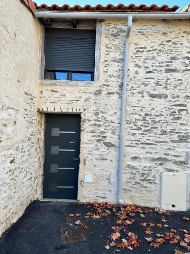 ein Gebäude mit einer schwarzen Tür und einem Fenster in der Unterkunft Maison au calme in Le Fief-Sauvin