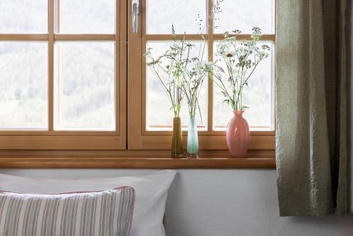 two vases on a window sill with flowers in them at Sloho Bergurlaub - Adults Only in Hohentauern