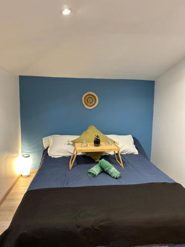 Una cama con un cabecero azul con una mesa. en Maison au calme en Le Fief-Sauvin