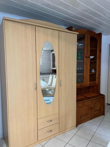 a wooden cabinet with a mirror in a room at Linh's Ferienwohnung in Saarburg