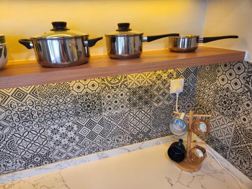 two pots on a shelf above a kitchen sink at Unique Boho Style Condo with NETFLIX for up to 5PAX - Enjoy Mountain View while swimming at the Infinity Pool & Natural Hotspring Pool, 2mins walk to the Lost World of Tambun, Water Themepark at IPOH in Ipoh