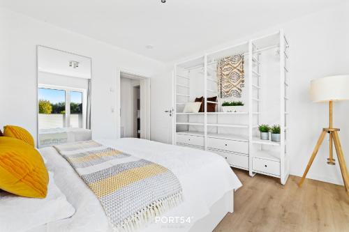 - une chambre blanche avec un lit et une lampe dans l'établissement Ferienwohnung Abenddämmerung, App 7 Emmelsbüll, à Emmelsbüll-Horsbüll