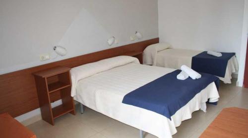 ein Hotelzimmer mit 2 Betten und einem Tisch in der Unterkunft Residencia Sant Jordi Llança in Llança