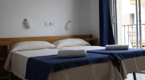 1 dormitorio con 2 camas con sábanas azules y ventana en Residencia Sant Jordi Llança en Llança
