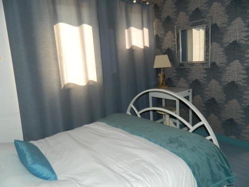 ein Schlafzimmer mit einem weißen Bett mit einer blauen Decke in der Unterkunft Le Clos Des Dryades d in Vers
