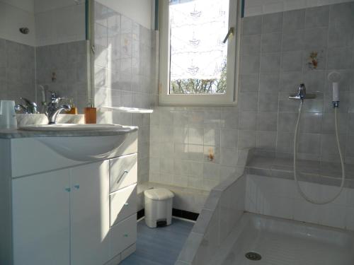 ein weißes Bad mit einem Waschbecken und einer Dusche in der Unterkunft Le Clos Des Dryades d in Vers