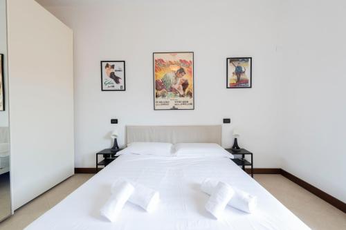 a white bed in a white room with pictures on the wall at Verona Movie Lovers in Verona