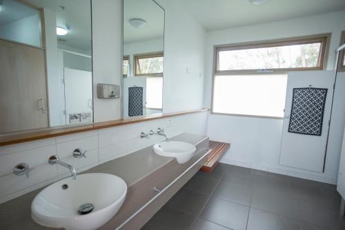 a white bathroom with a sink and a mirror at Apollo Bay Eco YHA in Apollo Bay