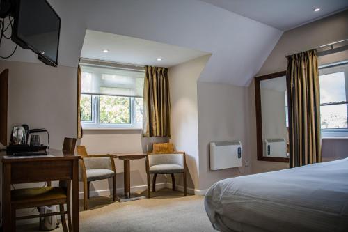 a hotel room with a bed and a desk and chairs at The Lodge At Meyrick Park in Bournemouth
