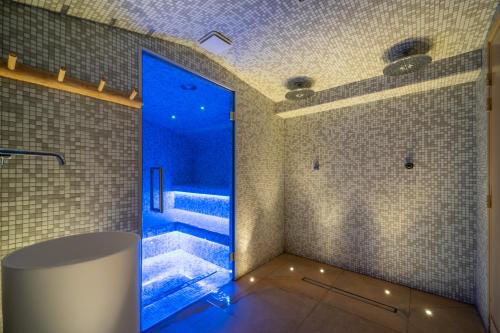 La salle de bains est pourvue d'une douche à l'italienne avec des lumières bleues. dans l'établissement La Finca Hôtel & Spa, à Paris