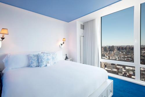 a bedroom with a white bed and a large window at NoMo SoHo in New York