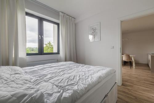 um quarto branco com uma cama grande e uma janela em Apartament w Dolinie Sanu nr 2 em Lesko