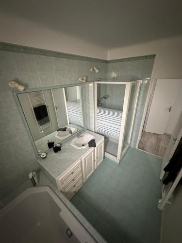 une salle de bain avec une baignoire, un lavabo et un miroir dans l'établissement Grand Mas Provençal rénové avec piscine-plage, à Cavaillon