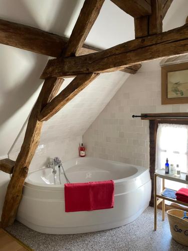 - une grande baignoire blanche dans une chambre dotée de plafonds en bois dans l'établissement Le grand Moulin, à Pernay