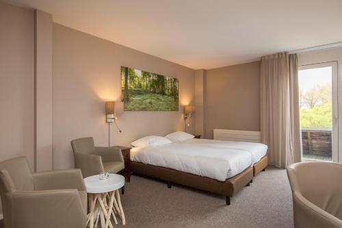 a hotel room with a bed and chairs and a window at Fletcher Hotel - Resort Spaarnwoude in Velsen-Zuid