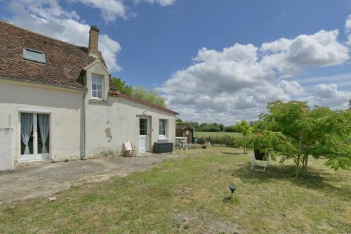 a white house with a yard with chairs and trees at Cozy Perche - Maison avec jardin in Cour-Maugis-sur-Huisne