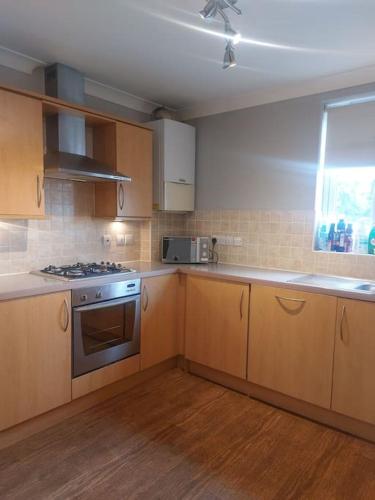uma cozinha com armários de madeira e um forno com placa de fogão em Short Stay at Dartford!!! em Dartford
