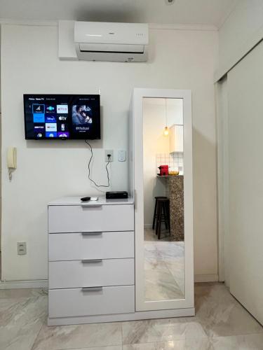 uma cómoda branca com um espelho e uma televisão na parede em Apartamento Moderno no Rio de Janeiro