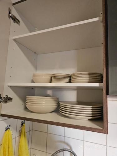 a cupboard filled with white plates and bowls at Komfortable 3-Zimmer-Wohnung in Neubeckum in Beckum