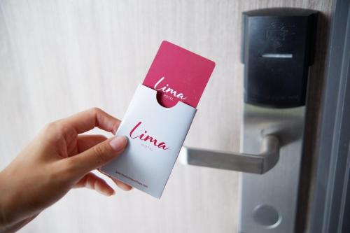 a person holding a card in front of a door at Lima Hotel in Phra Nakhon Si Ayutthaya