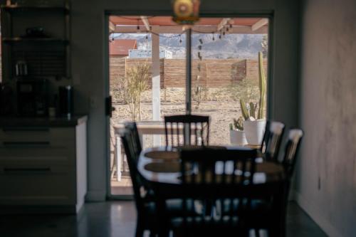 a dining room with a table and chairs and a window at Casa Del Desierto - Panoramic Views - Pet Friendly - Fire Pit in Joshua Tree