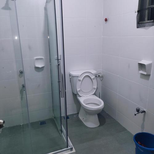 a bathroom with a toilet and a glass shower at Ummik Homestay in Tawau