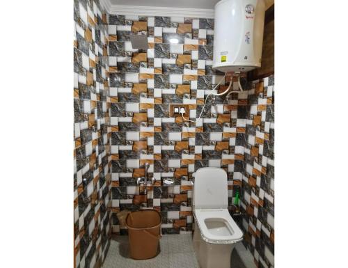 La salle de bains est pourvue de toilettes et d'un mur carrelé. dans l'établissement Ikhlas guest house, Srinagar, à Srinagar